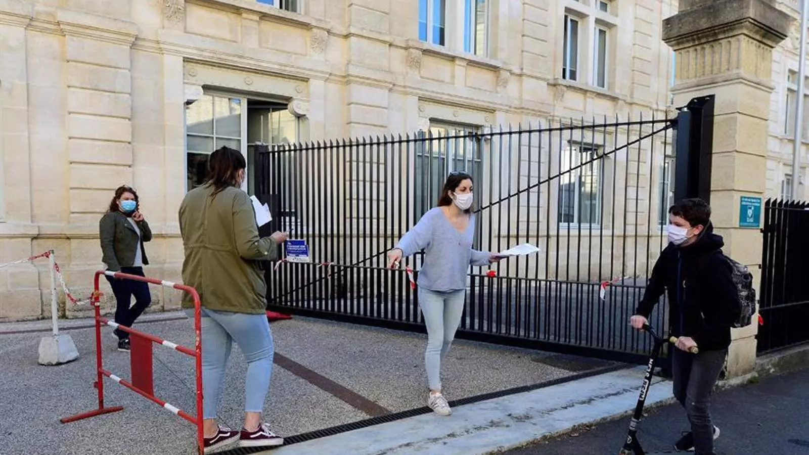 La supervisora d'una escola de Bordeus donant indicacions a un alumne, a la porta del centre en el primer dia de reinici del curs escolar