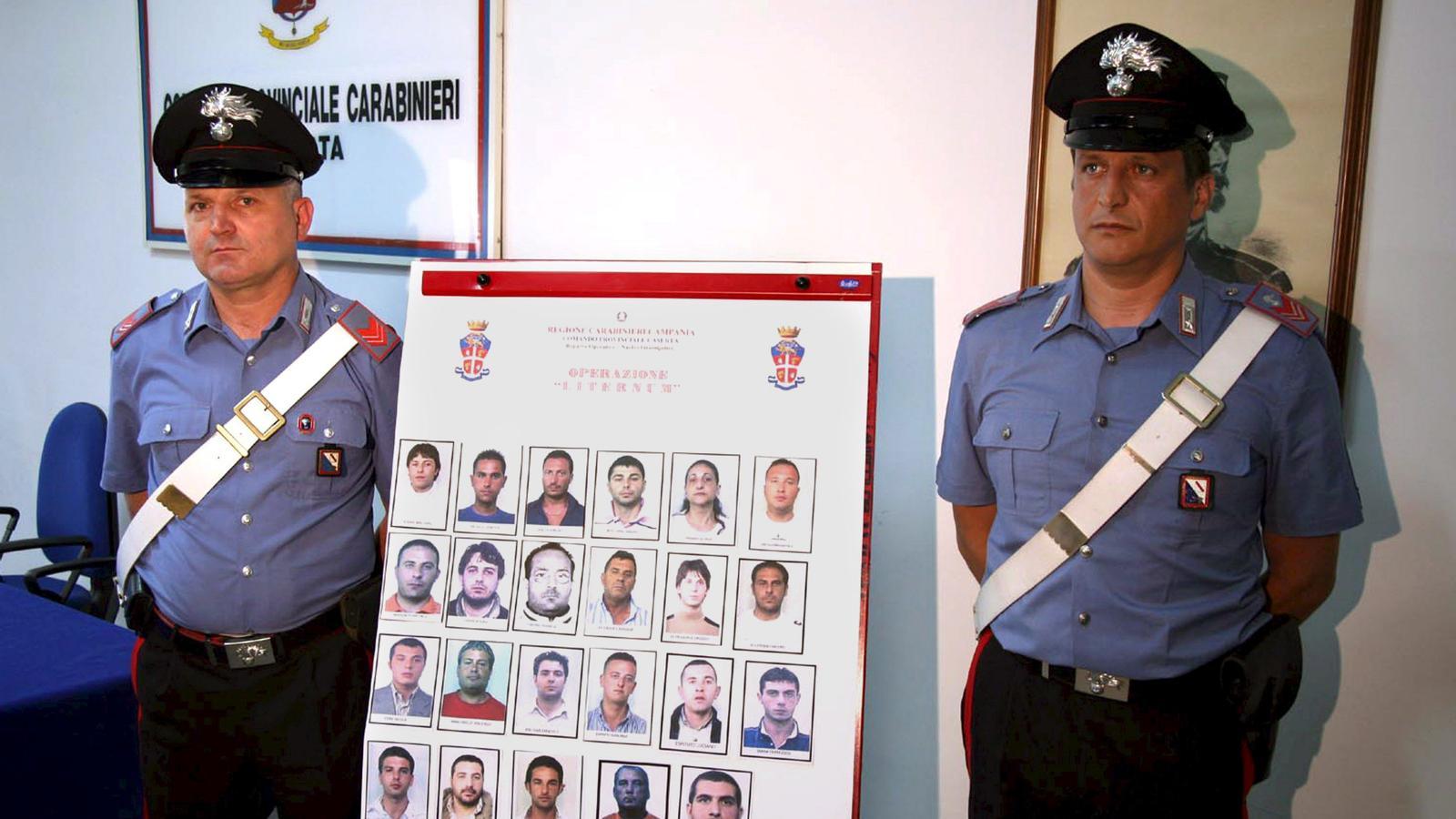 Dos carabineros italianos con un cartel que muestra personas arrestadas en operaciones contra la mafia