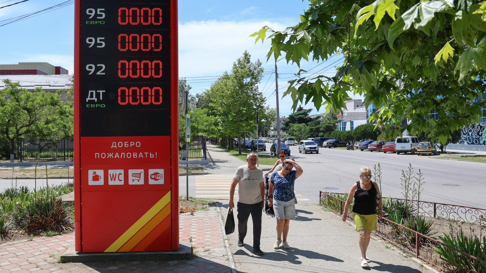 Pedestrians pass in front of a closed gas station after local authorities restricted the sale of gasoline due to scarcity.