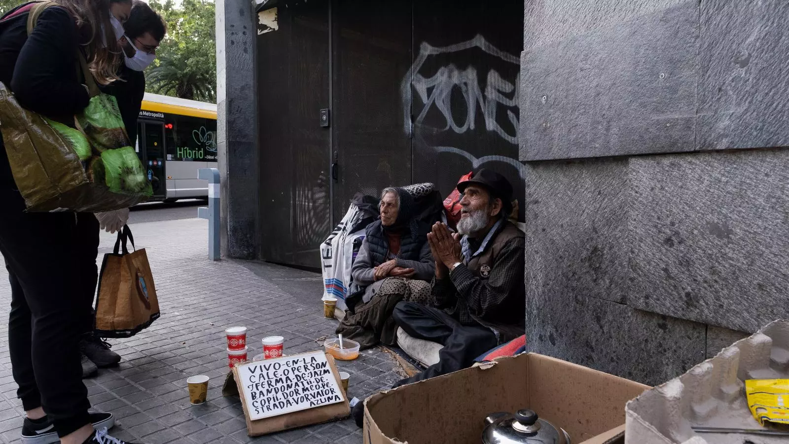 Dos voluntaris d'Arrels atenent a una parella que viu al carrer en ple confinament