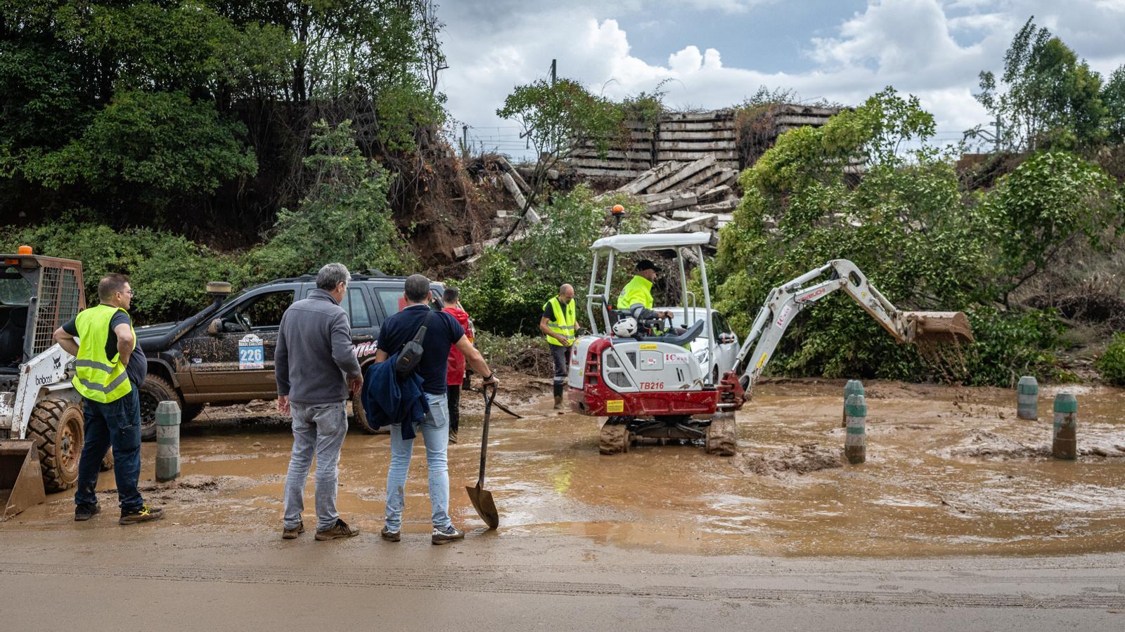 Workers remove mud accumulated by the collapse of an embankment on the R3 line of Rodalies