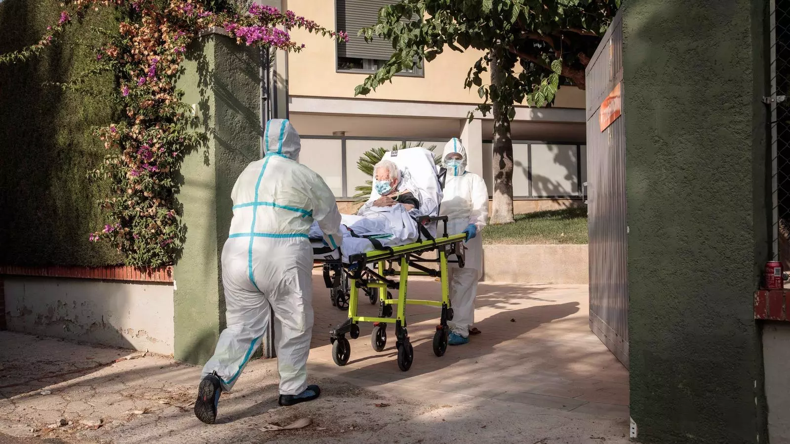 Dos treballadors sanitaris transporten una dona major a la residència de l'Eliana, on s'ha detectat un brot de coronavirus