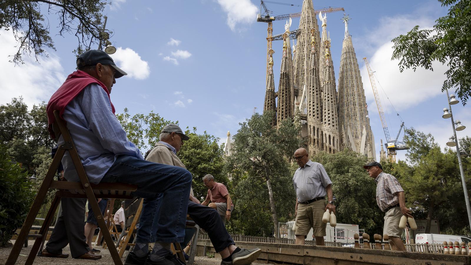 Vecinos de la Sagrada Familia jugando a los bolos catalanes con el templo detrás.