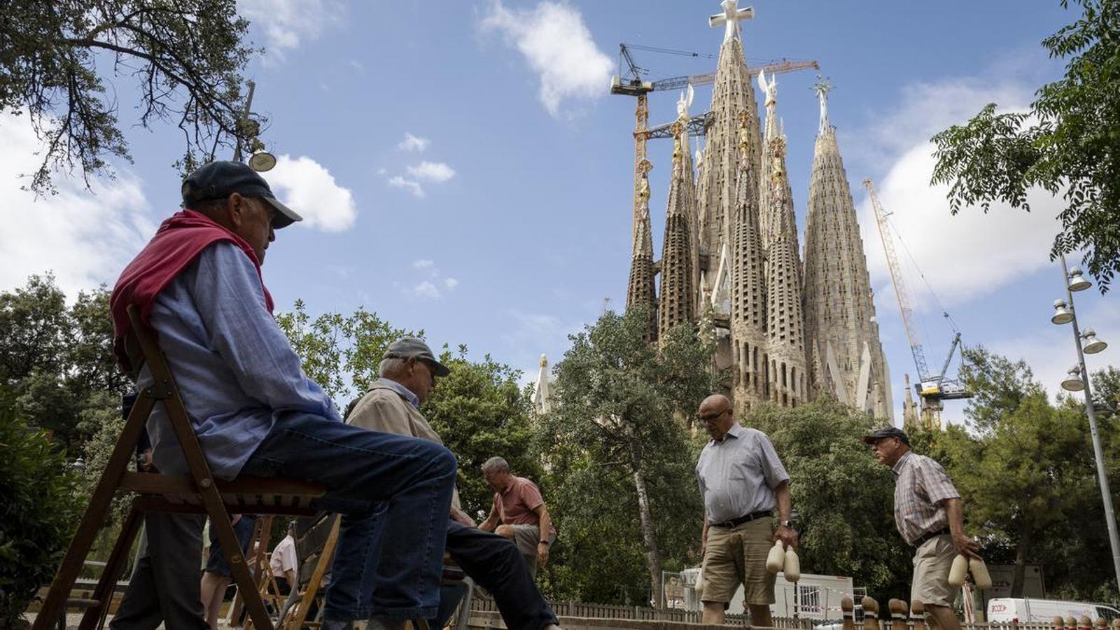 Vecinos de la Sagrada Familia jugando a los bolos catalanes con el templo detrás.