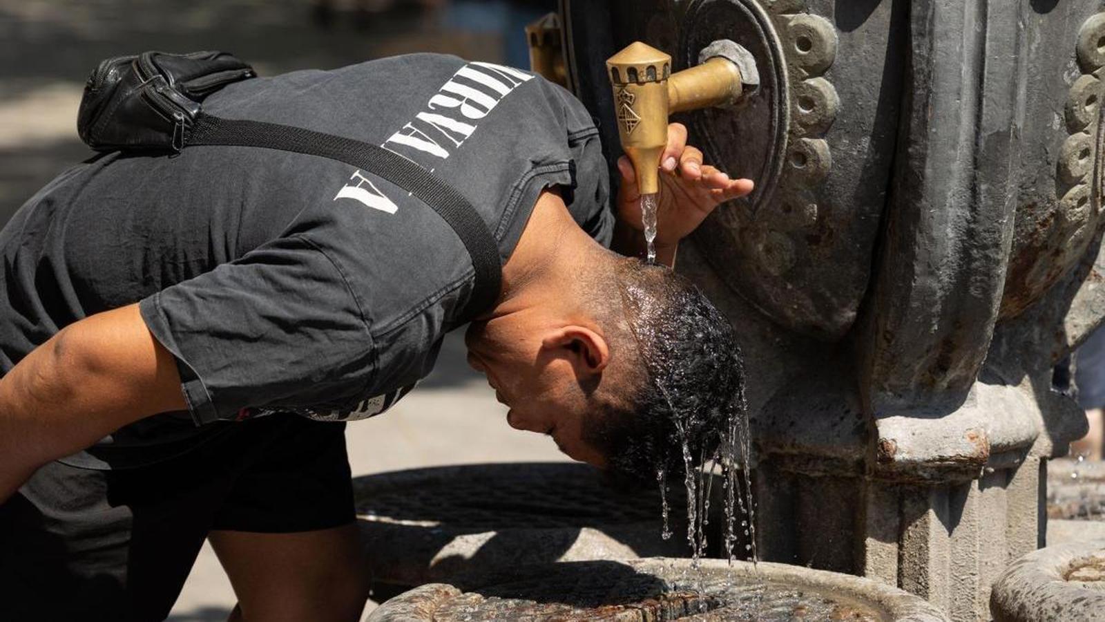 Un hombre se refresca en una fuente del centro de Barcelona durante la ola de calor de julio del 2026.