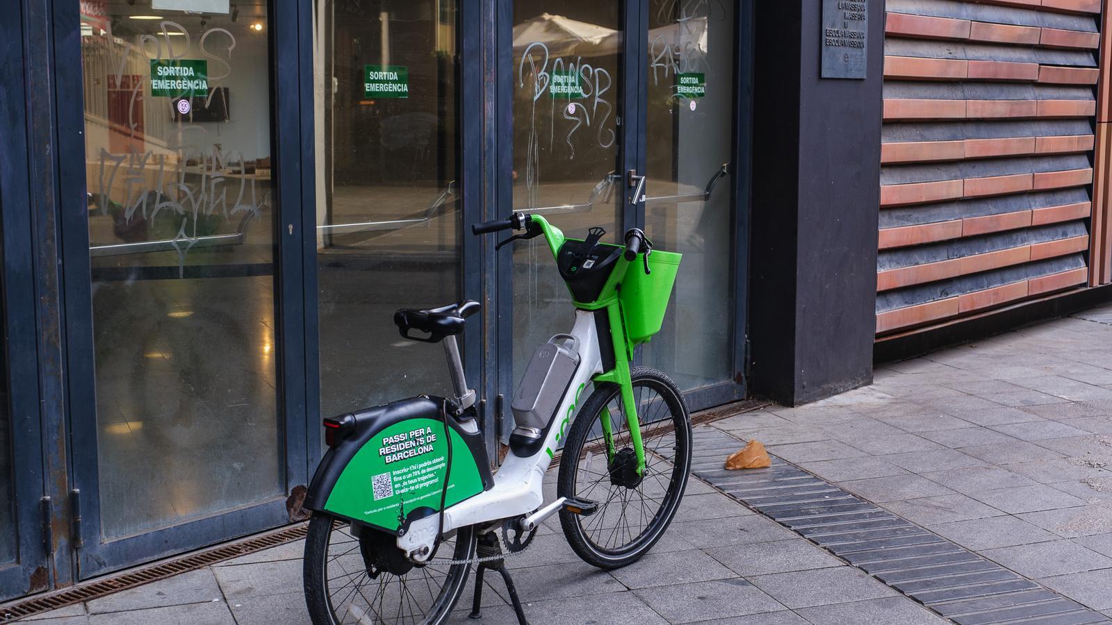 A shared bicycle parked in front of an emergency exit of the Massana School