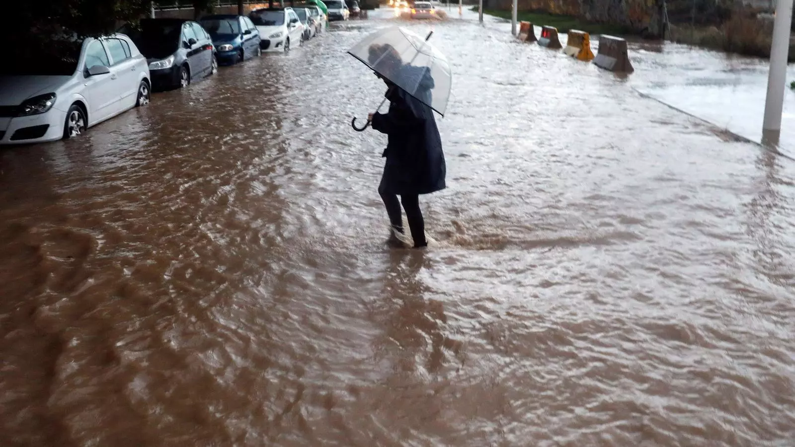 Una dona creu un carrer de València inundat per les fortes pluges registrades aquest divendres