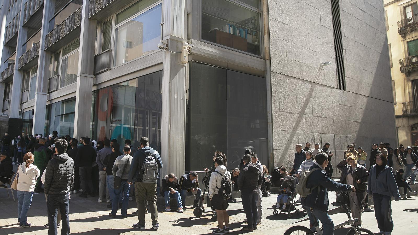 Cues d'immigrants davant de l'OAC del centre de Barcelona per sol·licitar els papers per a la regularització.
