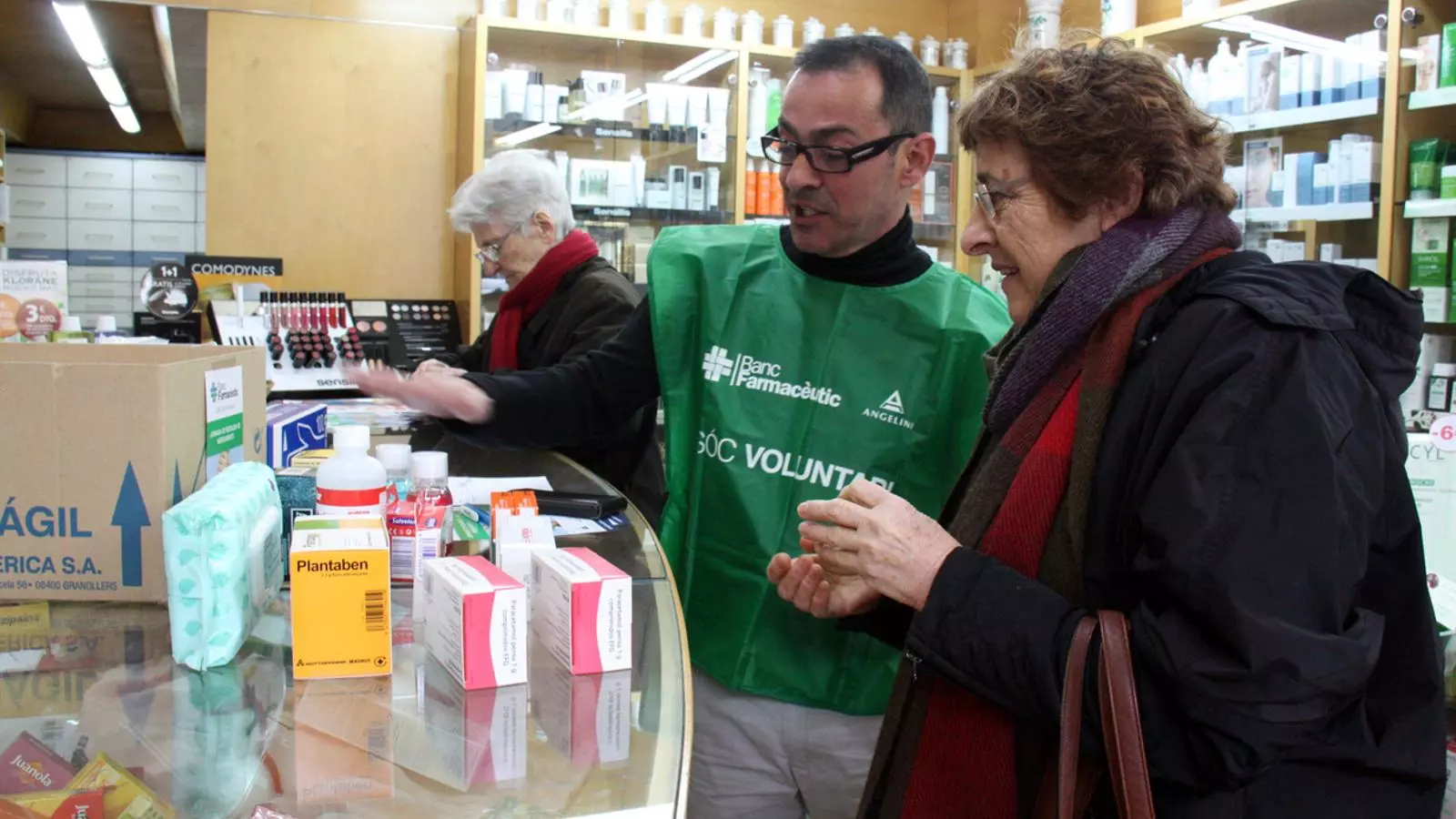 Un dels voluntaris explicant els medicaments que més necessiten a la seva entitat en una farmàcia de Girona / ACN