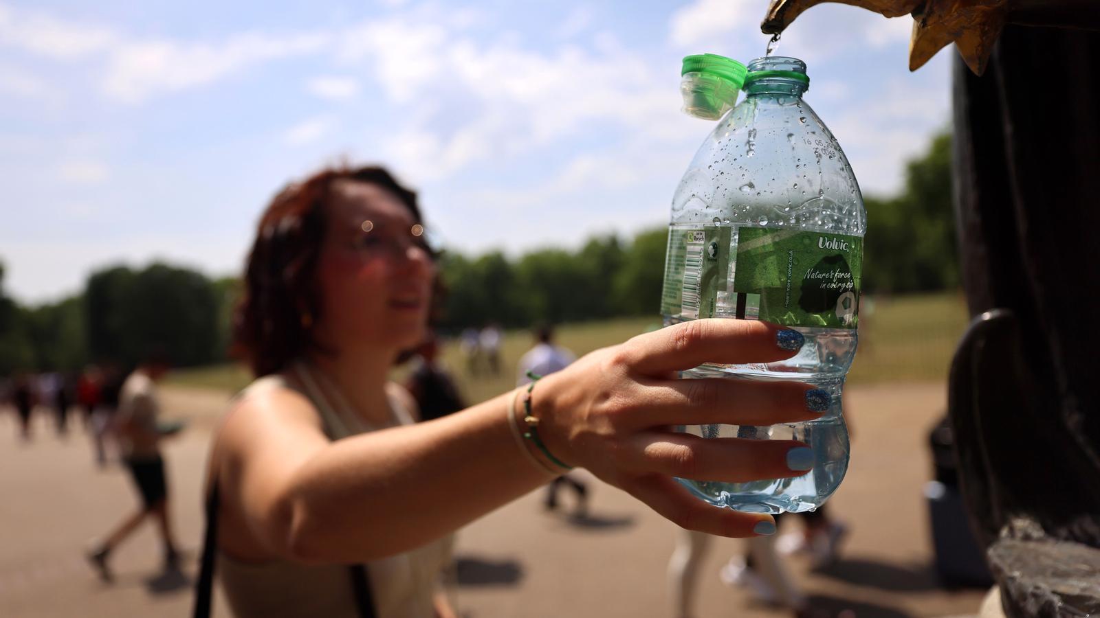 A woman fills a water bottle at a fountain in London during the extreme heatwave affecting the United Kingdom.