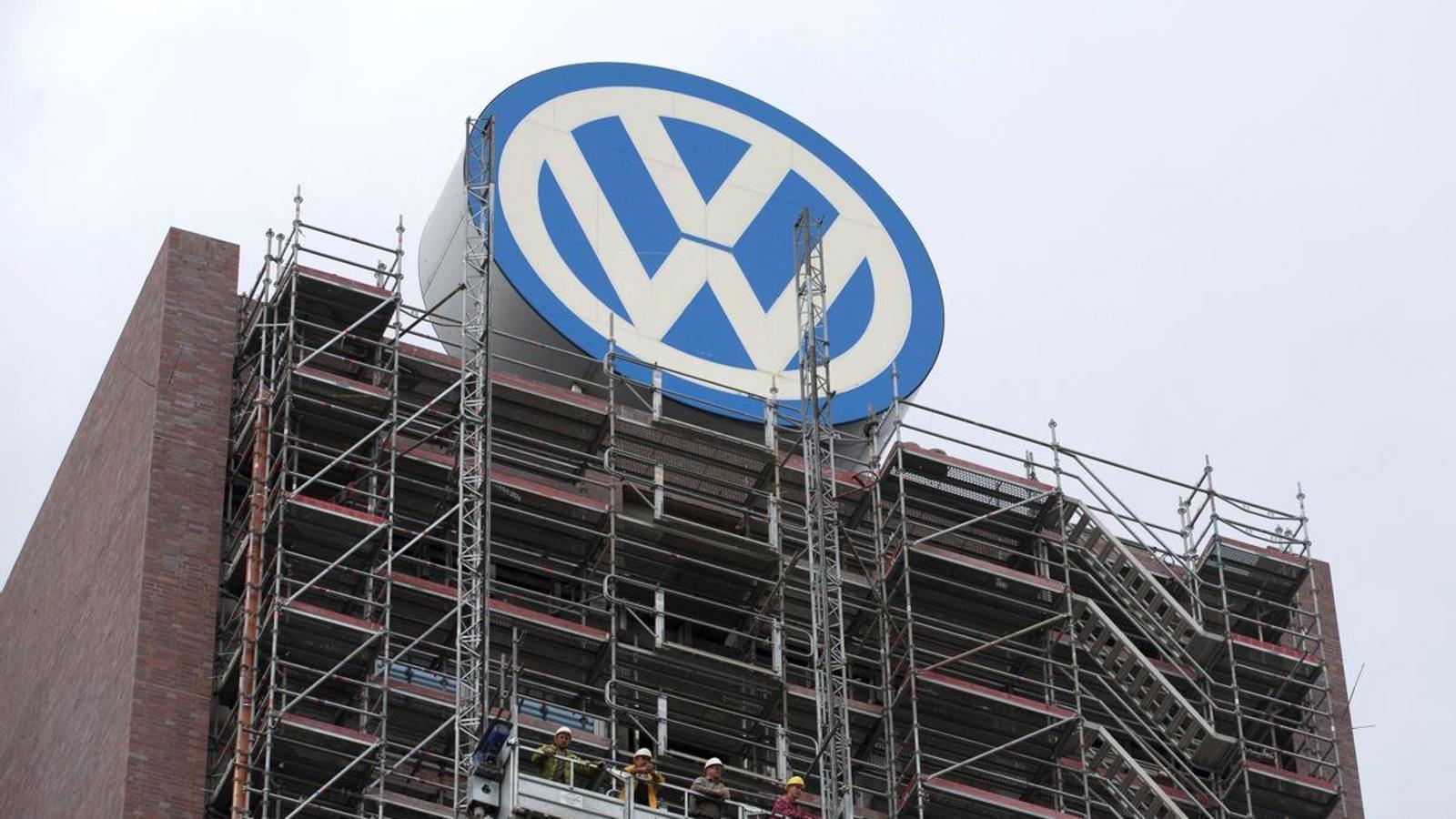 Workers under the Volkswagen logo on the facade of the group's headquarters in Wolfsburg (Germany).
