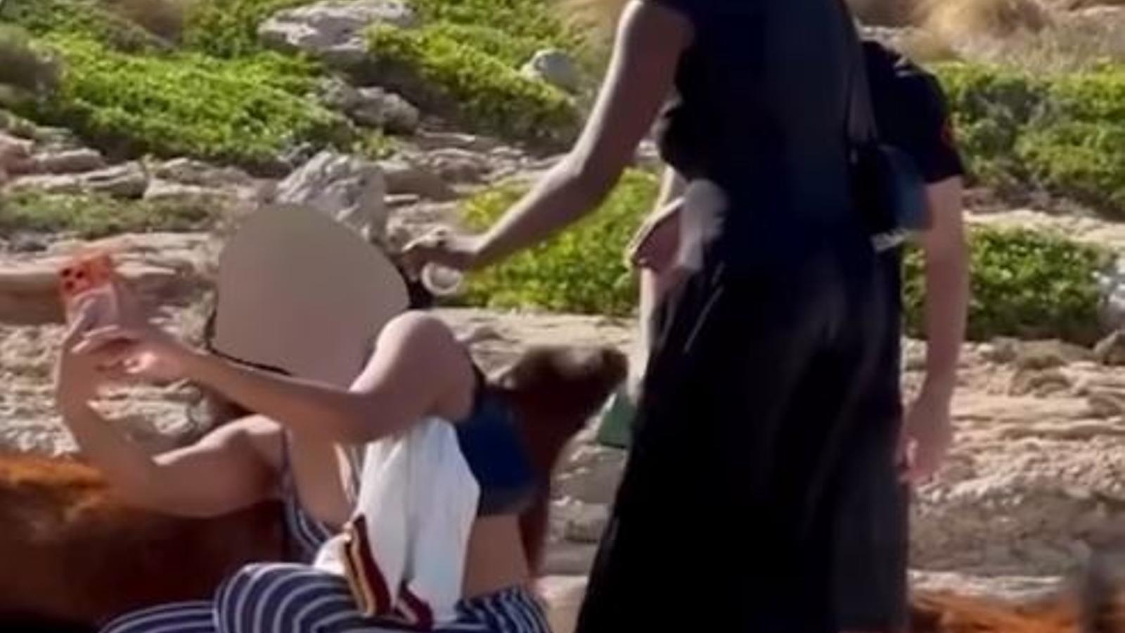 Persones donant cervesa a cabres a Cala Figuera.