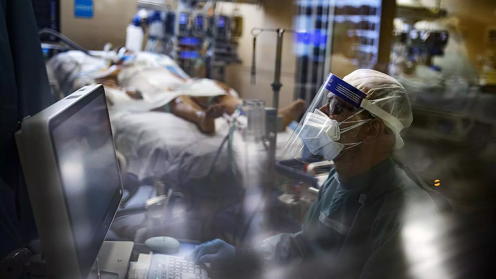 Un sanitari de l’Hospital de la Vall d’Hebron monitoritzant un malalt de covid-19 a l’UCI.