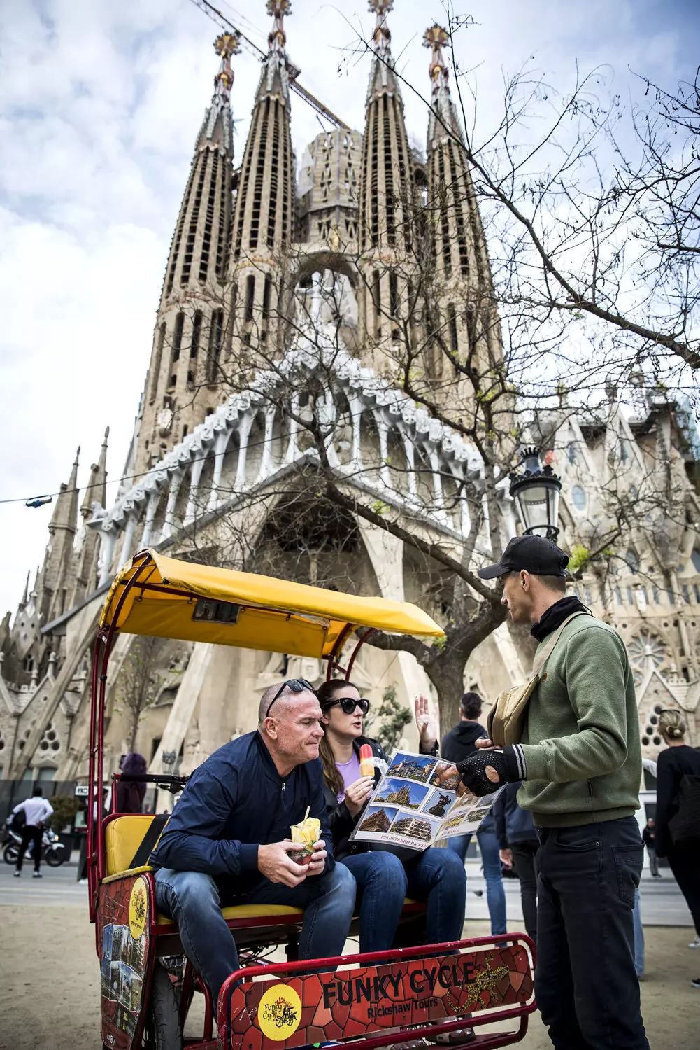 Turistes en bicitaxi ante la Sagrada Familia.
