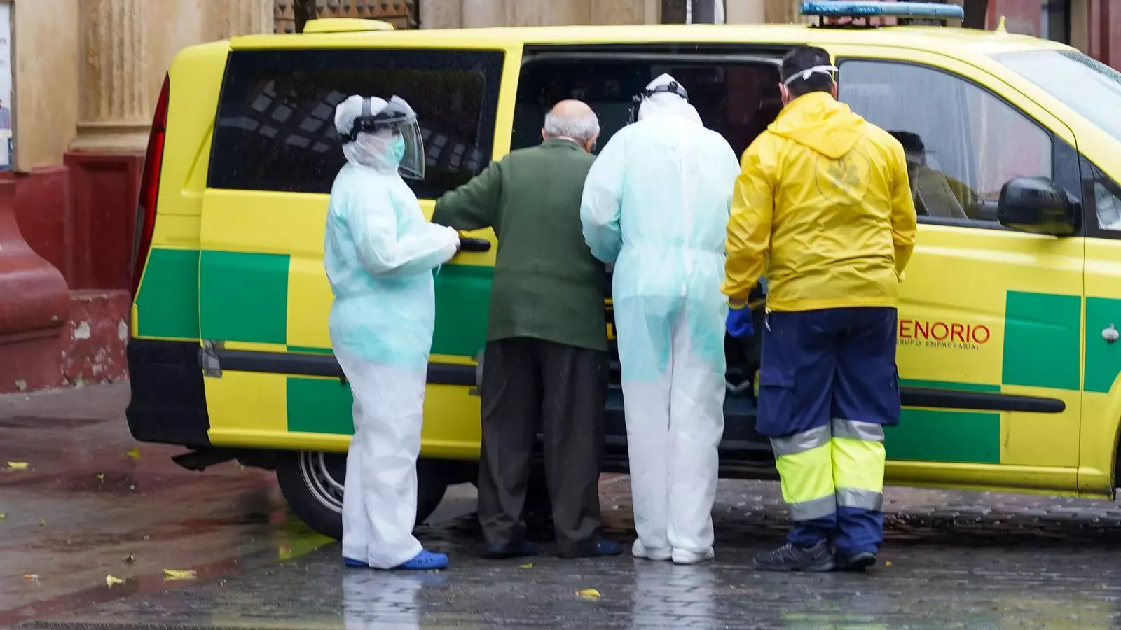 Sanitaris de la residència San Juan de Dios acompanyen un home gran cap a l'ambulància que el portarà a l'Hospital Virgen del Rocío de Sevilla