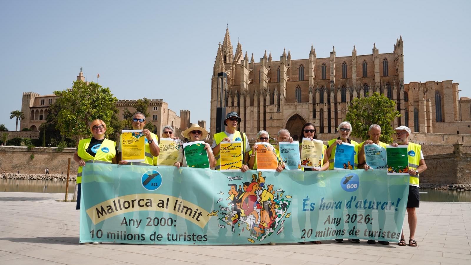 Representantes del GOB y Terraferida sostienen la pancarta para la manifestación del 26-J.