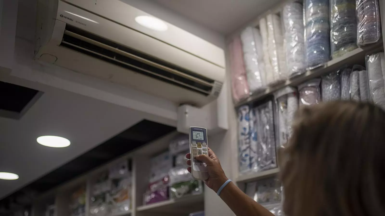 Una mujer regula la temperatura del aire acondicionado