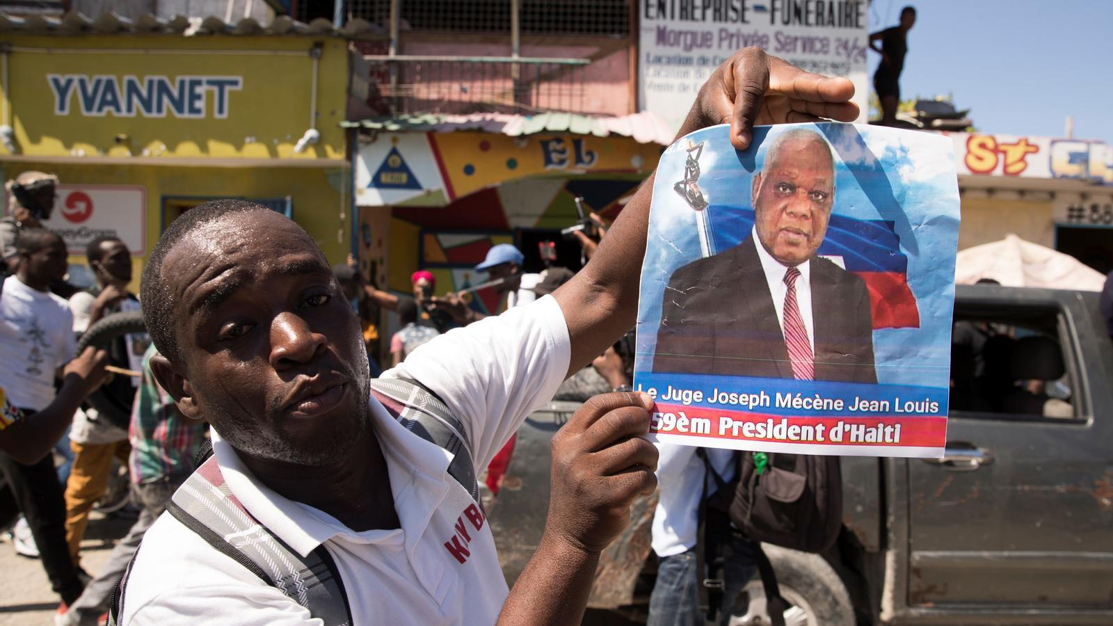 A Haitian protester holds up a photo of self-proclaimed president Joseph Mécène Jean Louis