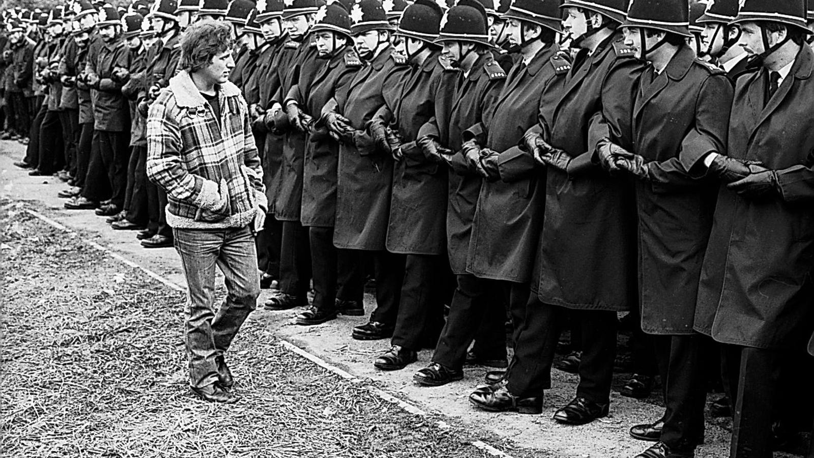 Miner Eric Hudson 'inspects' the guard of police officers on the front line at the Orgreave coking plant, near Sheffield, Yorkshire, on Monday, June 4, 1984, two weeks before the serious clashes that are now the subject of a public inquiry.
