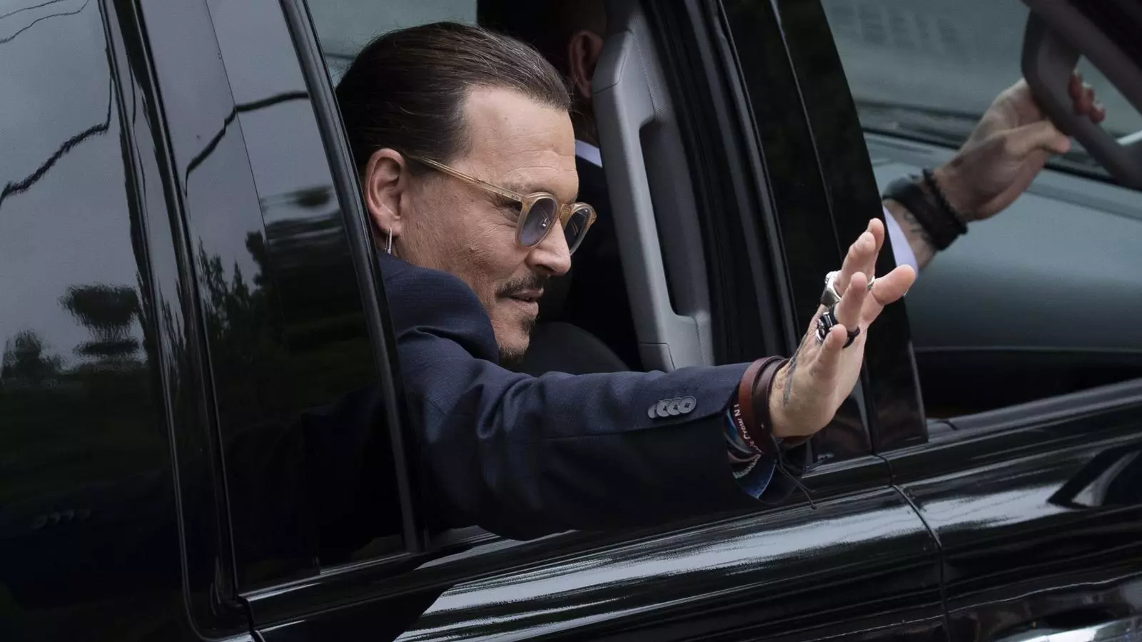 Johnny Depp saluda sus seguidores a la salida de los juzgados.