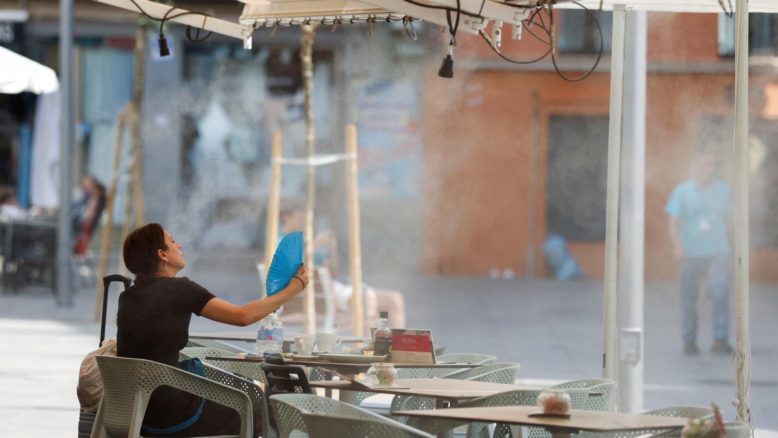 A woman uses a handheld fan to cool off during the first heat wave of the summer in Seville, Spain, June 30, 2025. REUTERS/