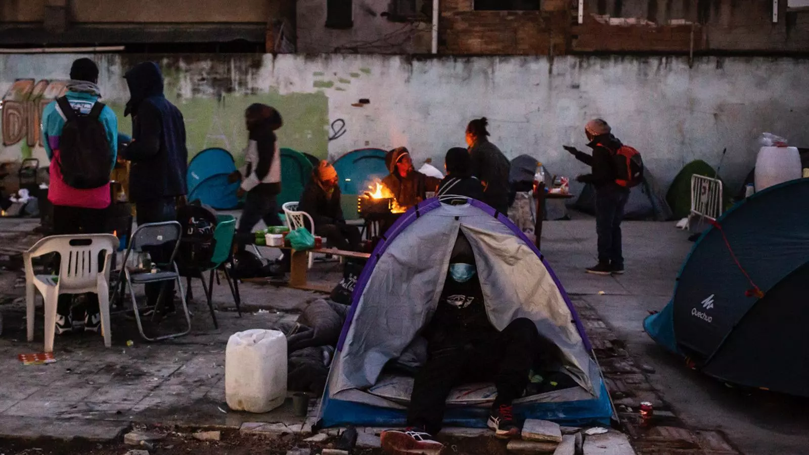 Campament de gent al descampat de l'antiga nau que es va cremar al desembre de 2020