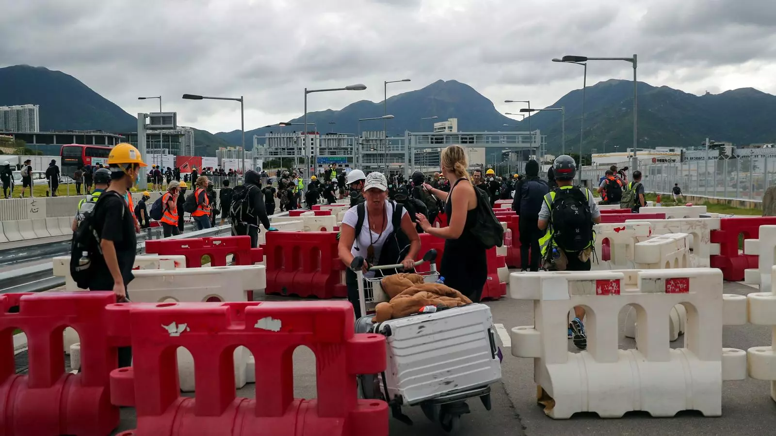 Usuaris de l'aeroport de Hong Kong passant entre les barricades que han desplegats els manifestants en una nova jornada de protestes