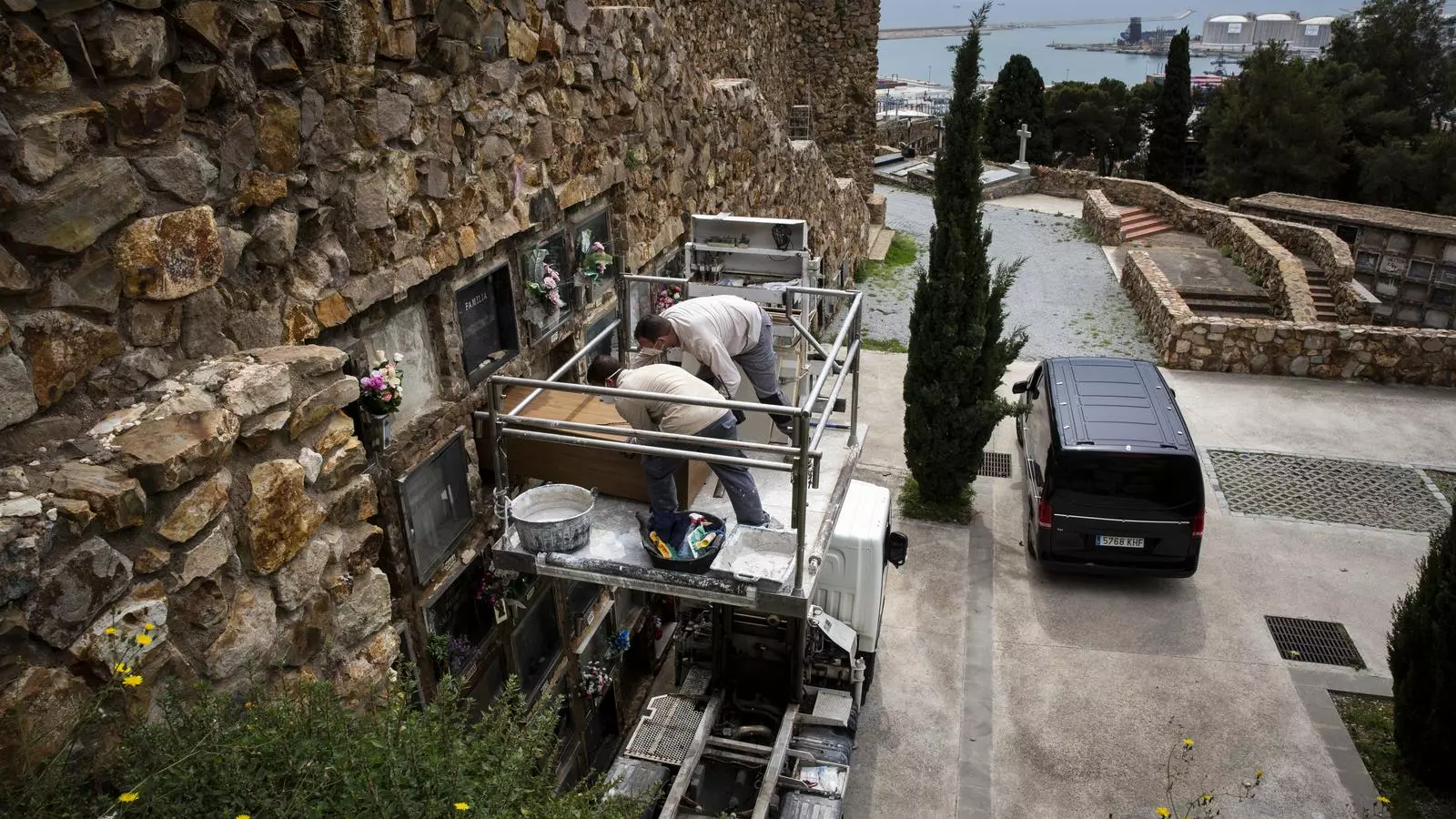 Una brigada d'enterradors inhuma un fèretre a un nínxol del cementiri de Montjuïc durant la crisi del coronavirus, a Barcelona, sense familiars presents