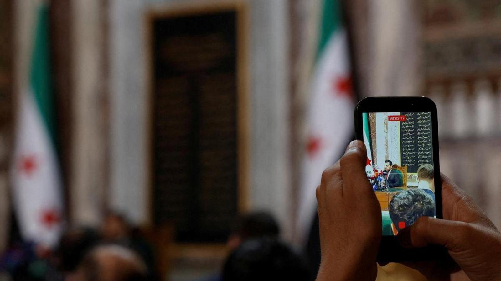 Un móvil alzado graba el anuncio de los legisladores escogidos para formar parte del parlamento de transición después de la era Assad.