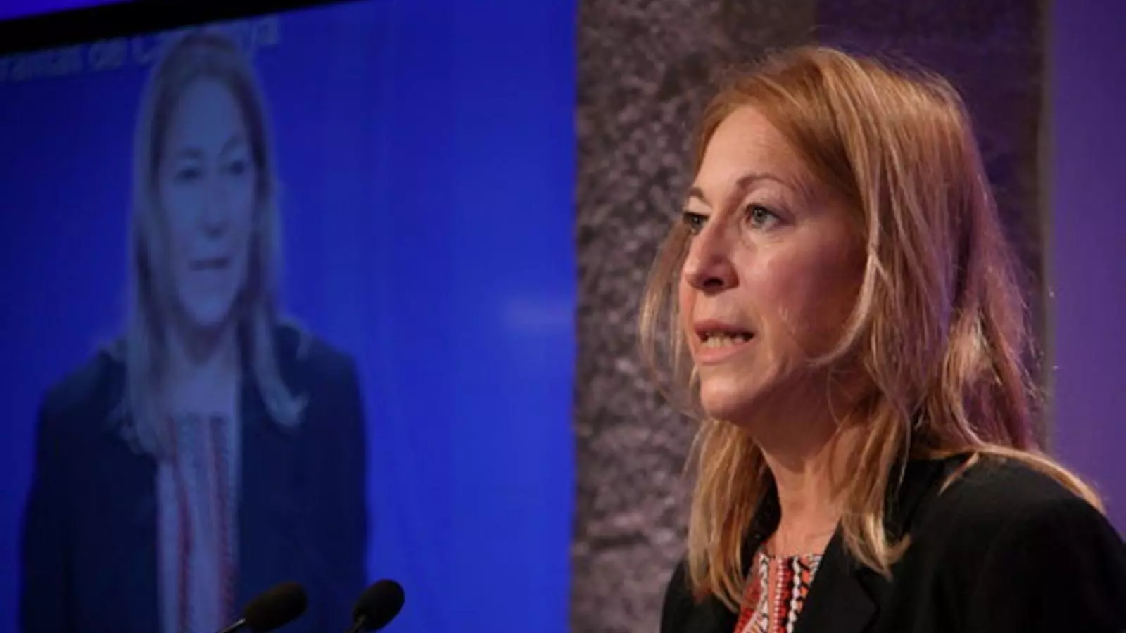 La portaveu del Govern, Neus Munté, amb una imatge seva a la pantalla, en una roda de premsa
