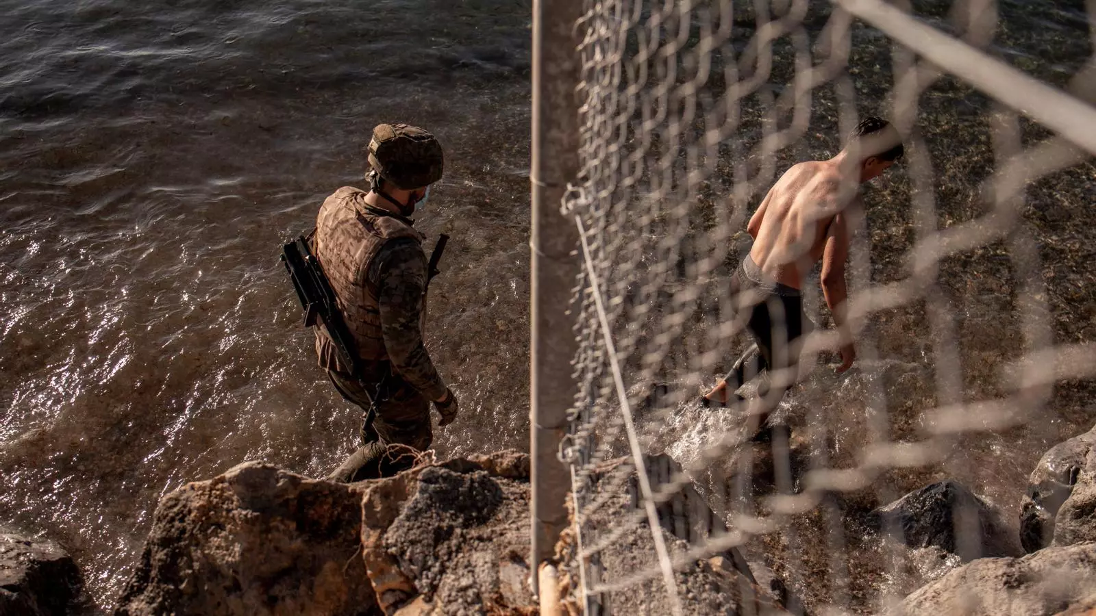 Un soldado del ejército español y un joven que ha llegado nadando en la playa del Tarajal, en Ceuta.