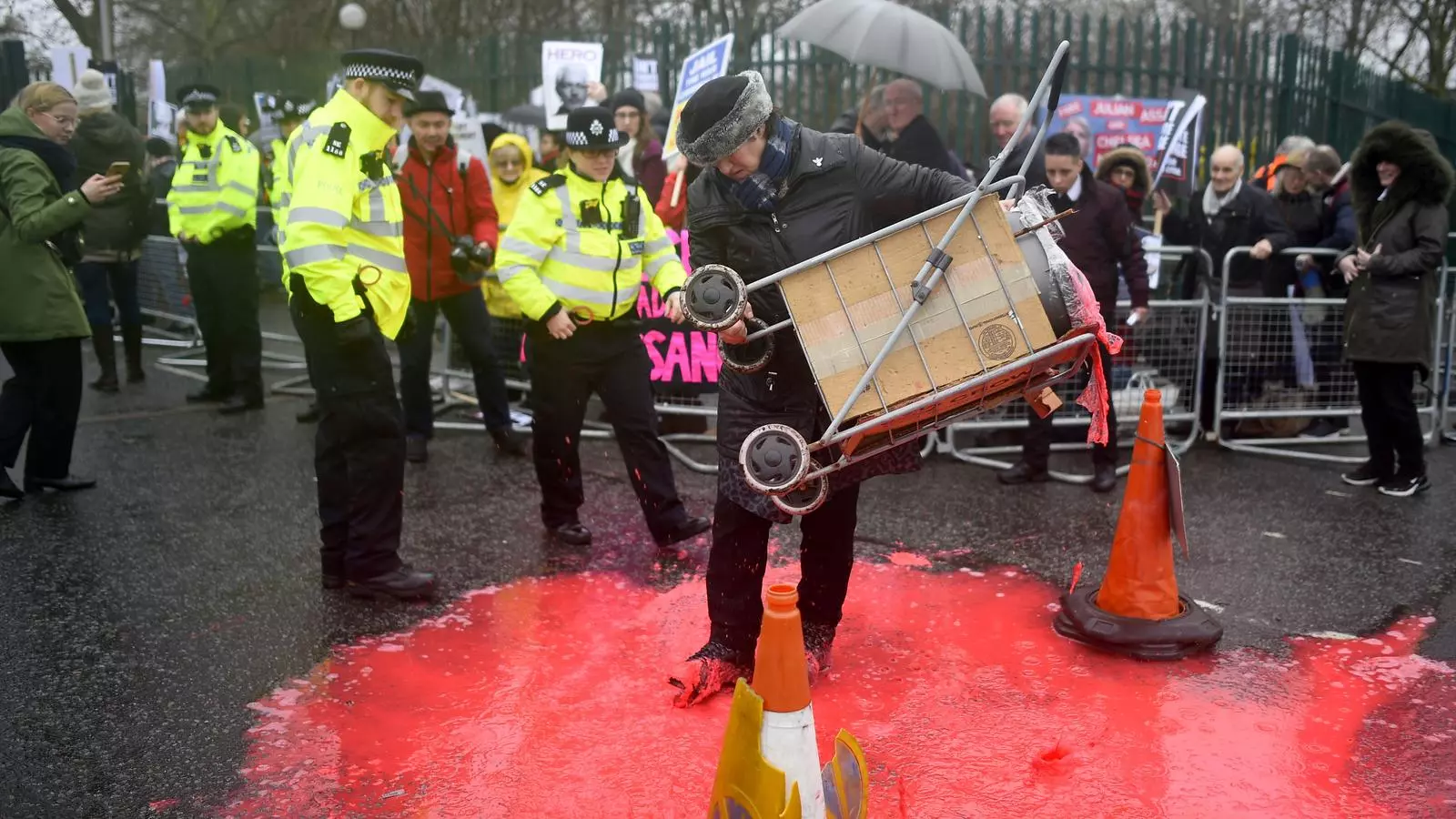 Una manifestant en suport de Julian Assange vessa pintura vermella a les portes del tribunal on té lloc el judici per l'extradició del fundador de Wikileaks als Estats Units, aquest dilluns, al sud de Londres
