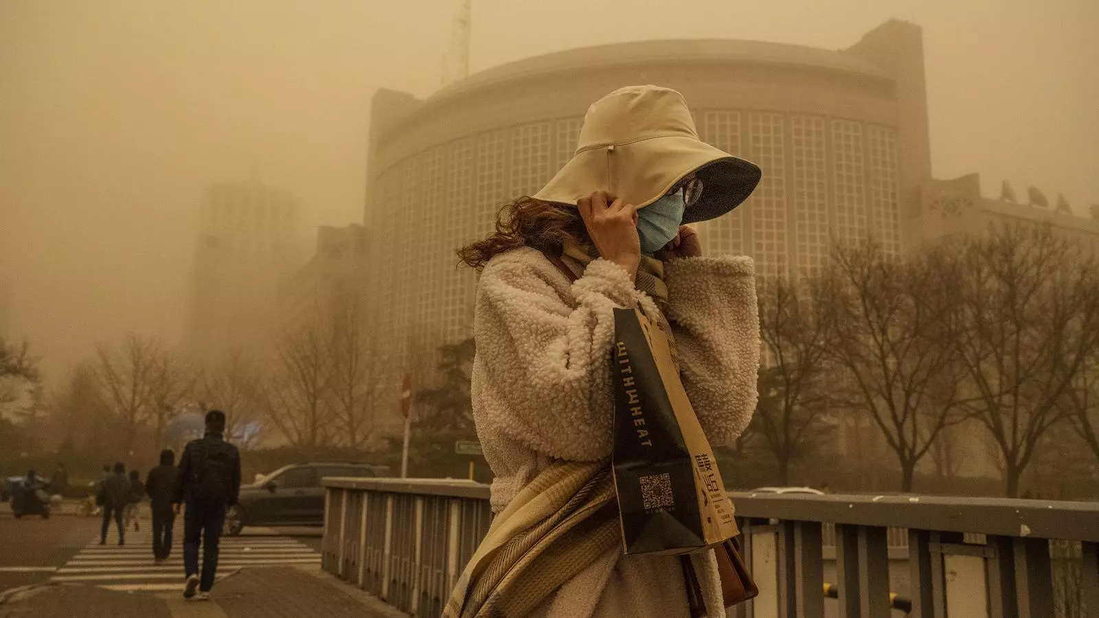 Una dona protegint-se dels forts vents durant una tempesta de sorra el 15 de març del 2021 a Pequín. La capital xinesa i la zona nord del país van rebre dilluns una tempesta de sorra que va disparar els índexs de qualitat de l’aire de PM 2,5 i PM 10 a milers i va obligar a cancel·lar vols.