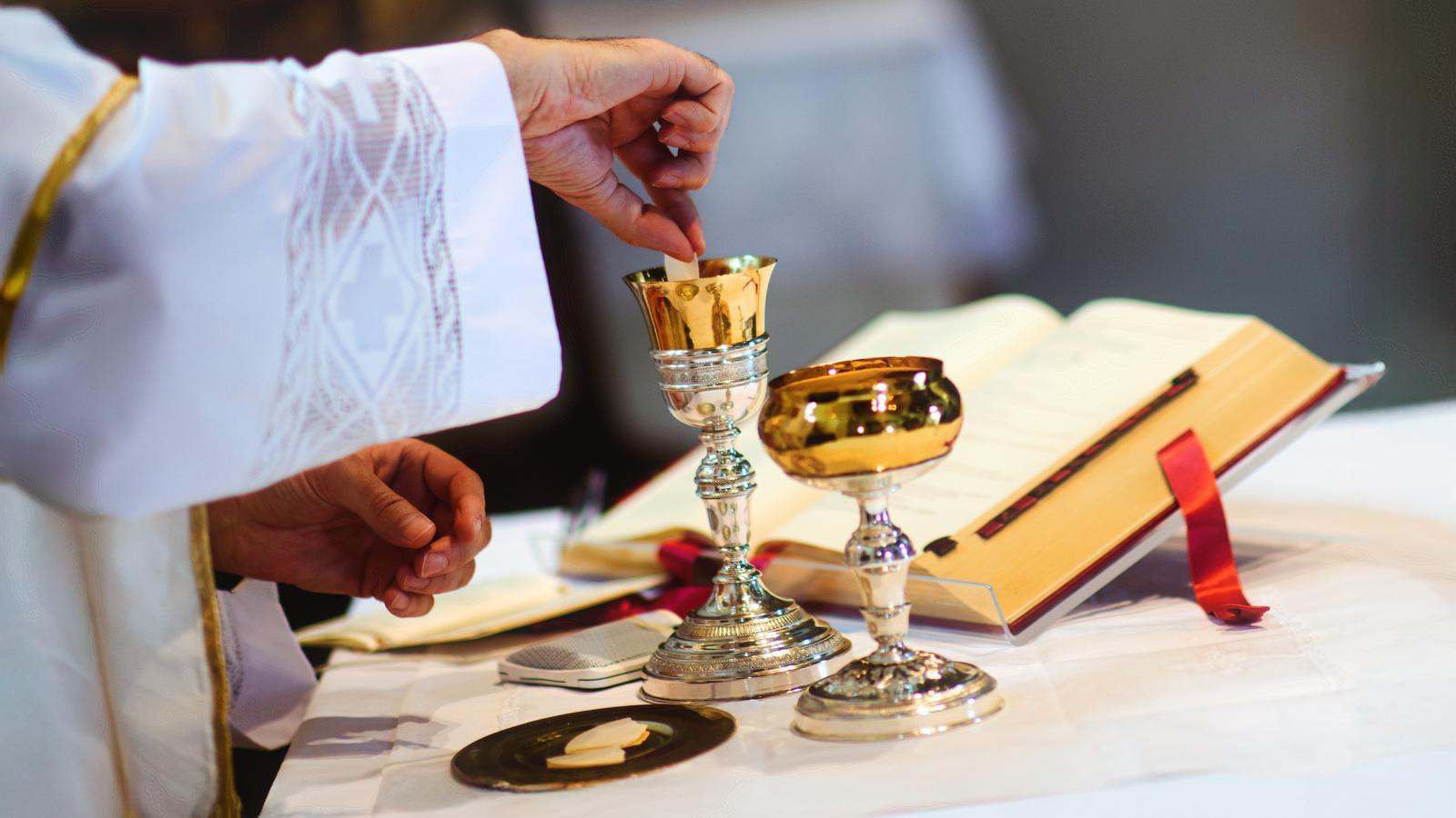 Un sacerdote sumerge la hostia consagrada en el vino durante el rito de la comunión en una iglesia.