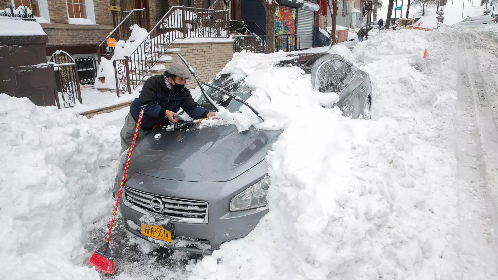 Un home treient neu del seu cotxe aquest matí a Brooklyn / REUTERS
