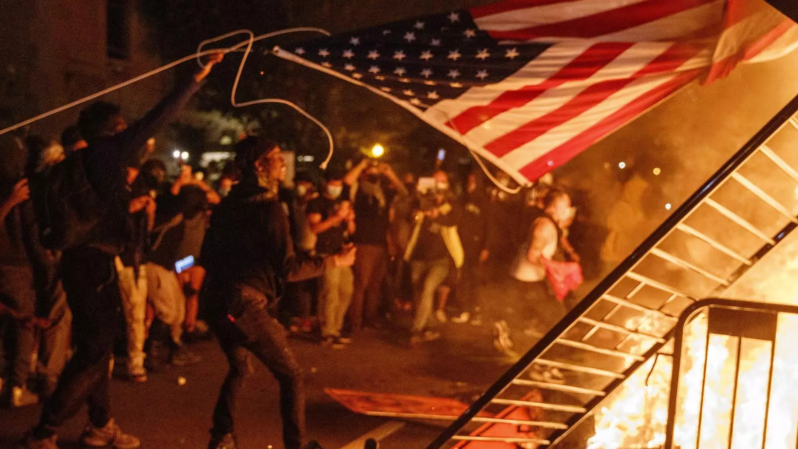 Manifestants cremant una barricada sota una bandera nord-americana, a prop de la Casa Blanca