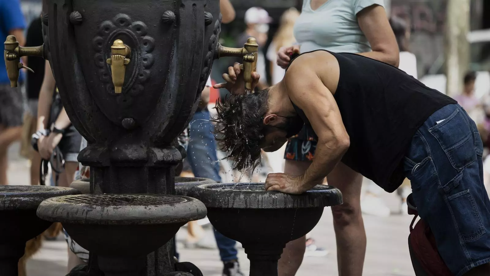 Un home refrescat-se a la Rambla de Barcelona a mitjans d'agost