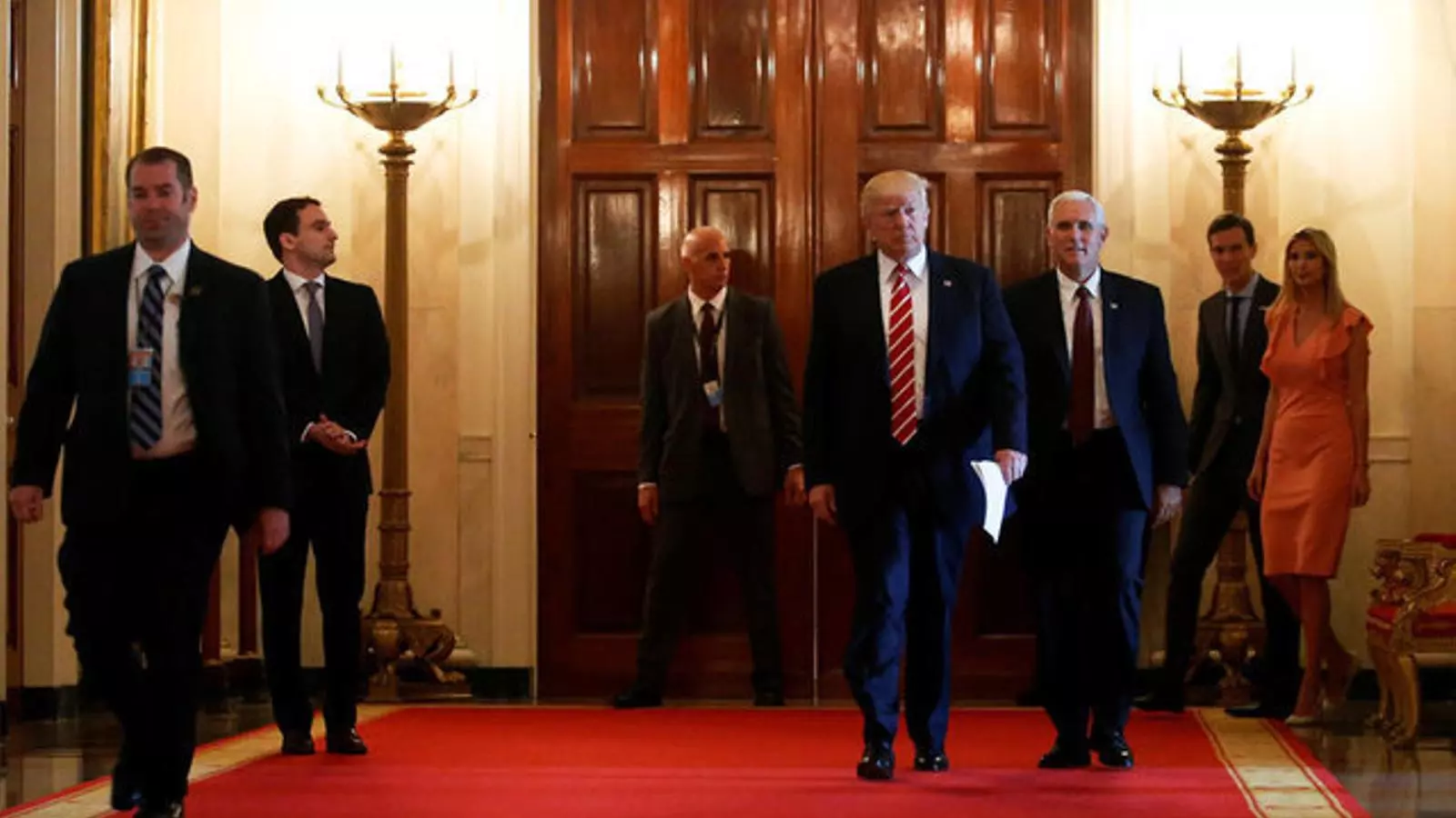 Trump camina per un passadís de la Casa Blanca, seguit pel seu vicepresident, la filla i el gendre.