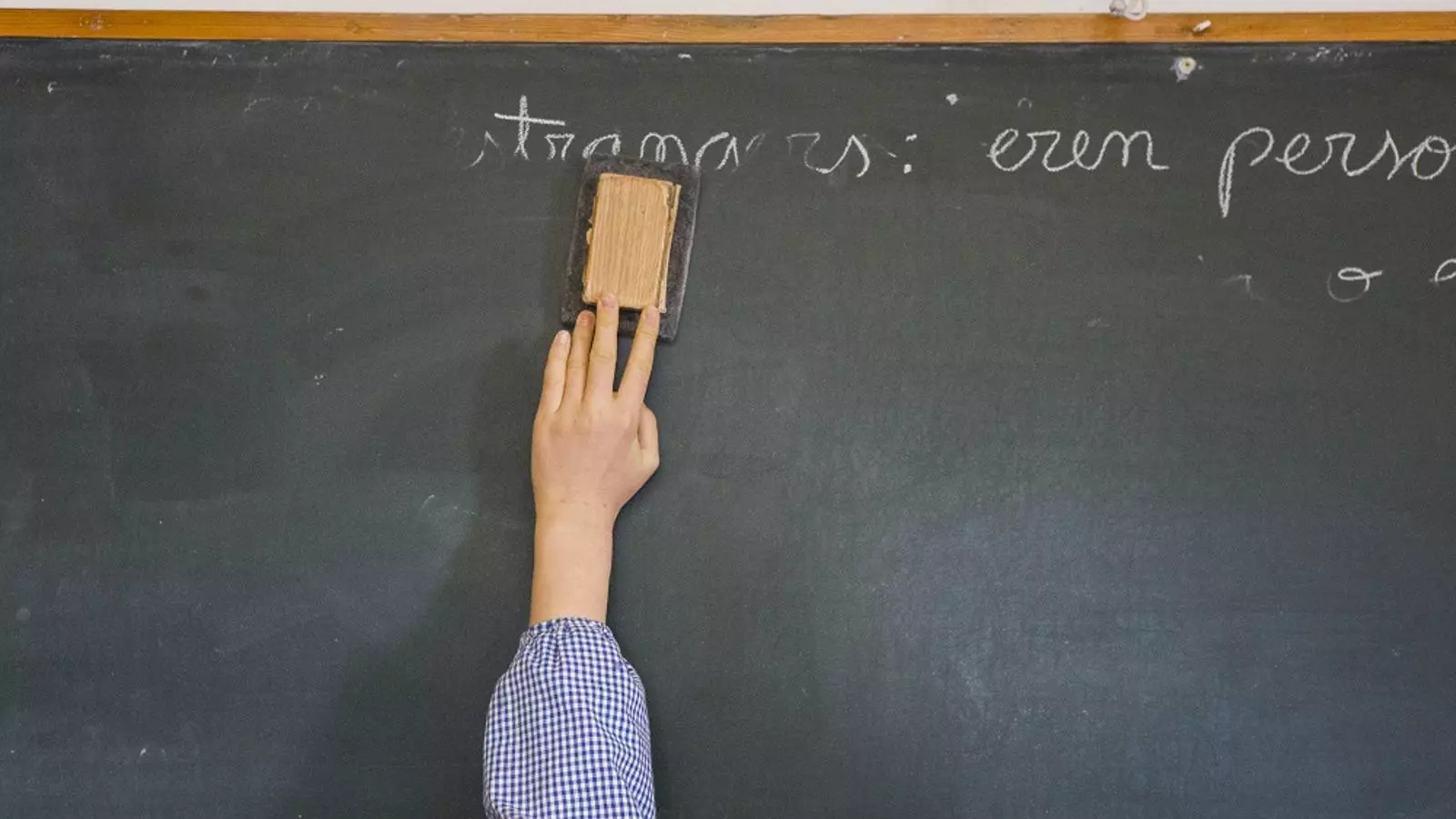 Un alumno borra la pizarra en una escuela de primaria.