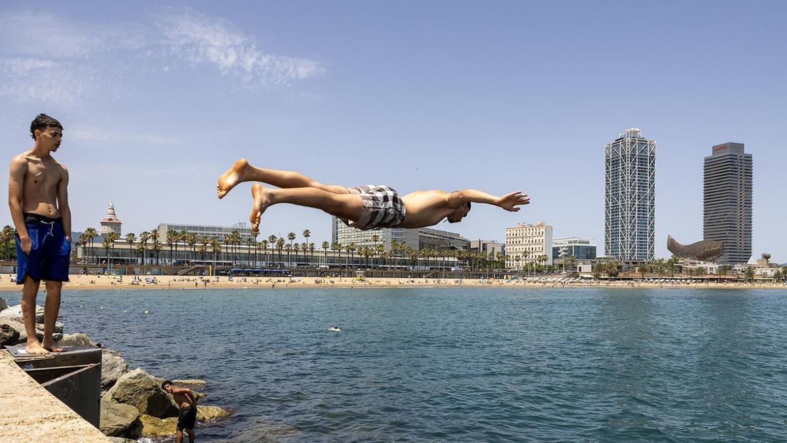 Jóvenes saltando desde el espigón de la Barceloneta, el 20 de junio.