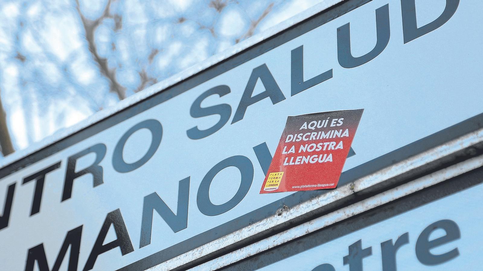 Un adhesiu de la Plataforma per la Llengua en un senyal del Centre de Salut de Palmanova que està en castellà.