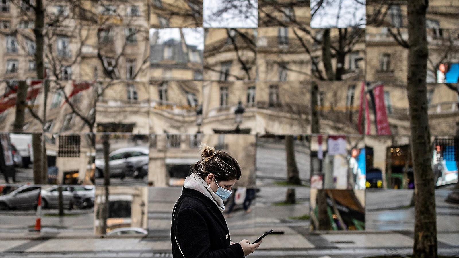 A woman walking down the street wearing a mask.