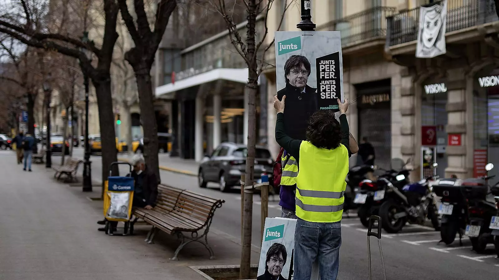 Un voluntari col·locant un cartell de JxCat en un fanal.