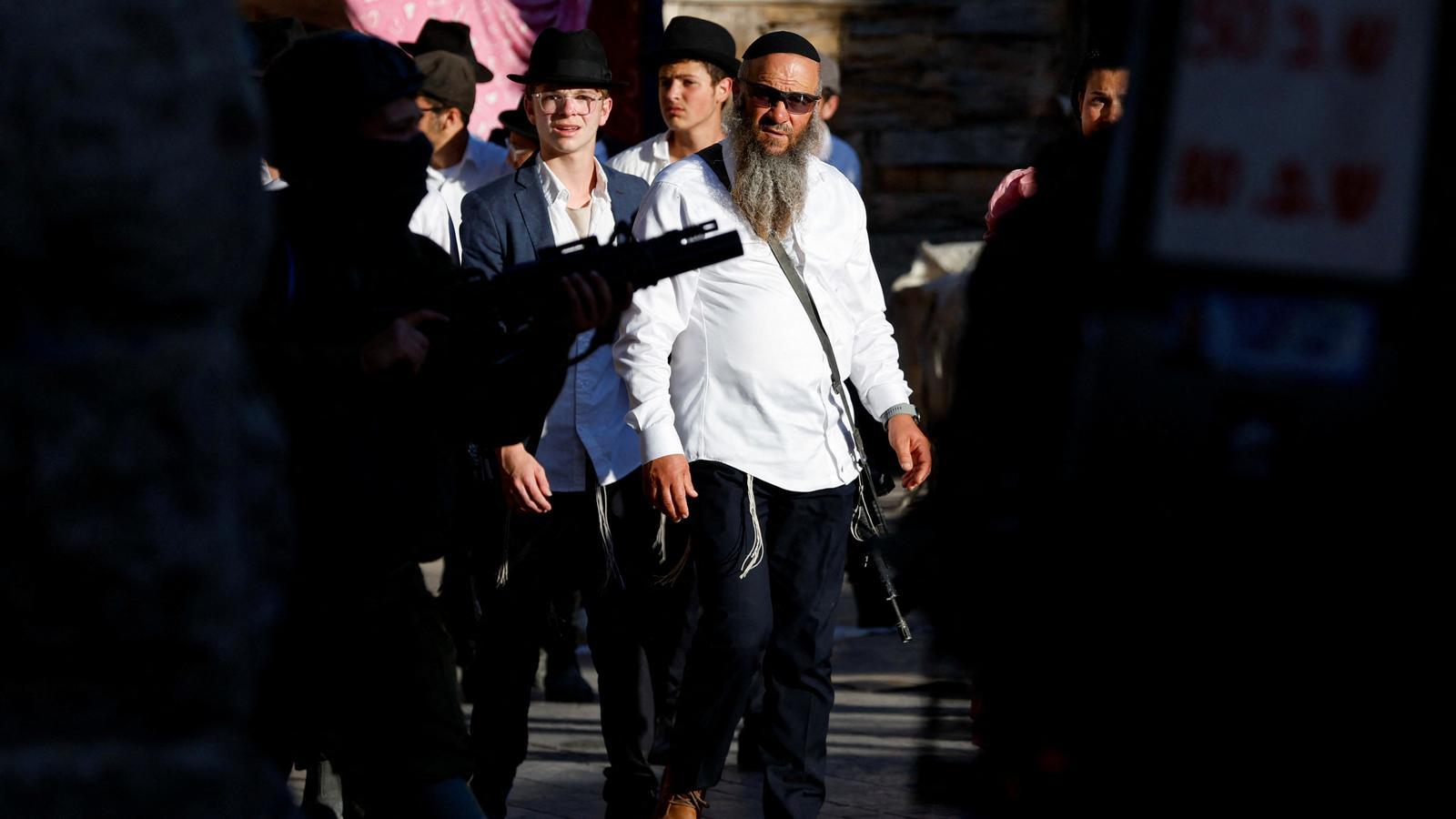 Settlers look on as Israeli soldiers stand guard during a weekly settler visit to Hebron in the occupied West Bank.