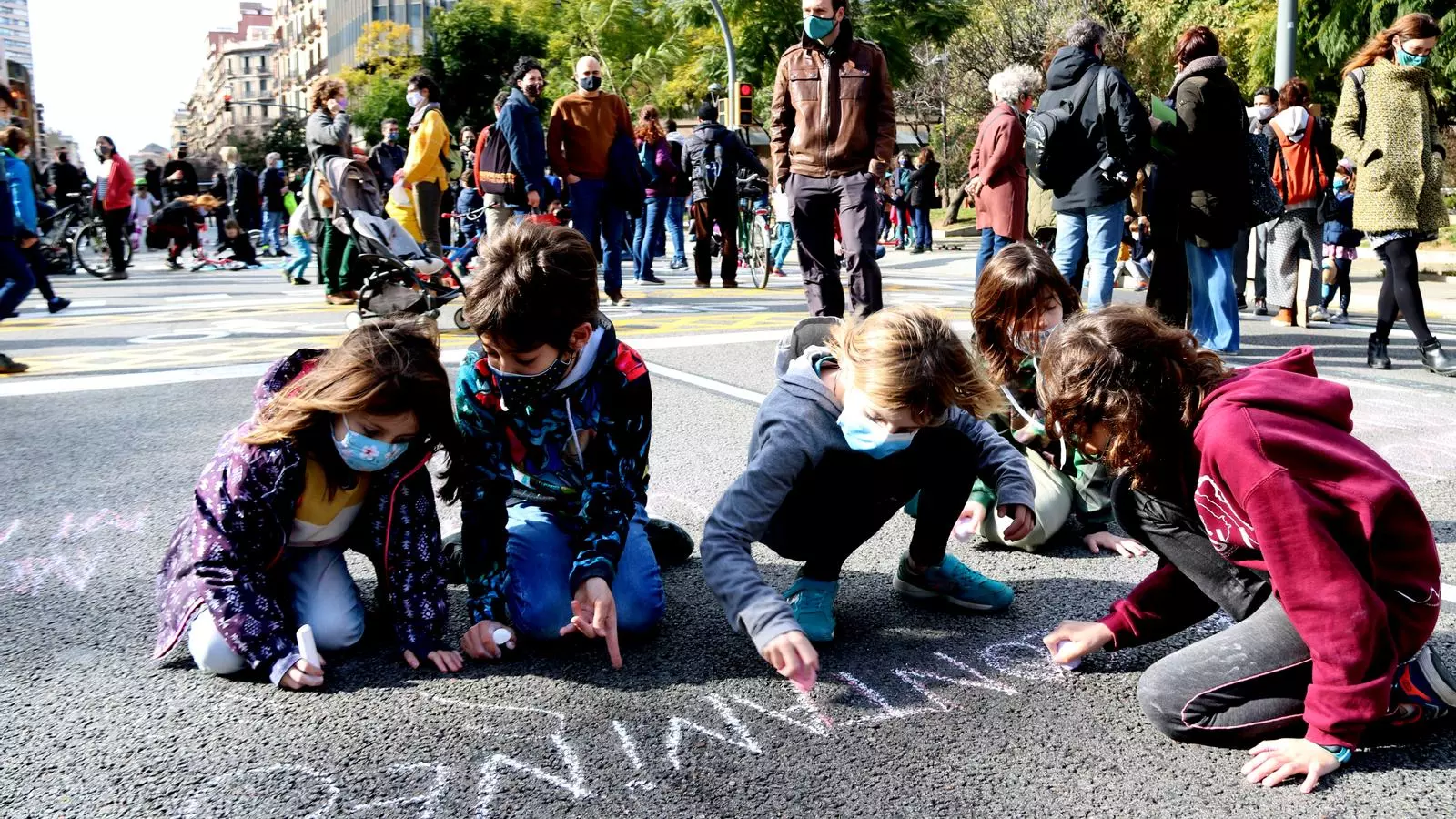 Un grup de nens pintant a terra en el tall del carrer Aragó de Barcelona