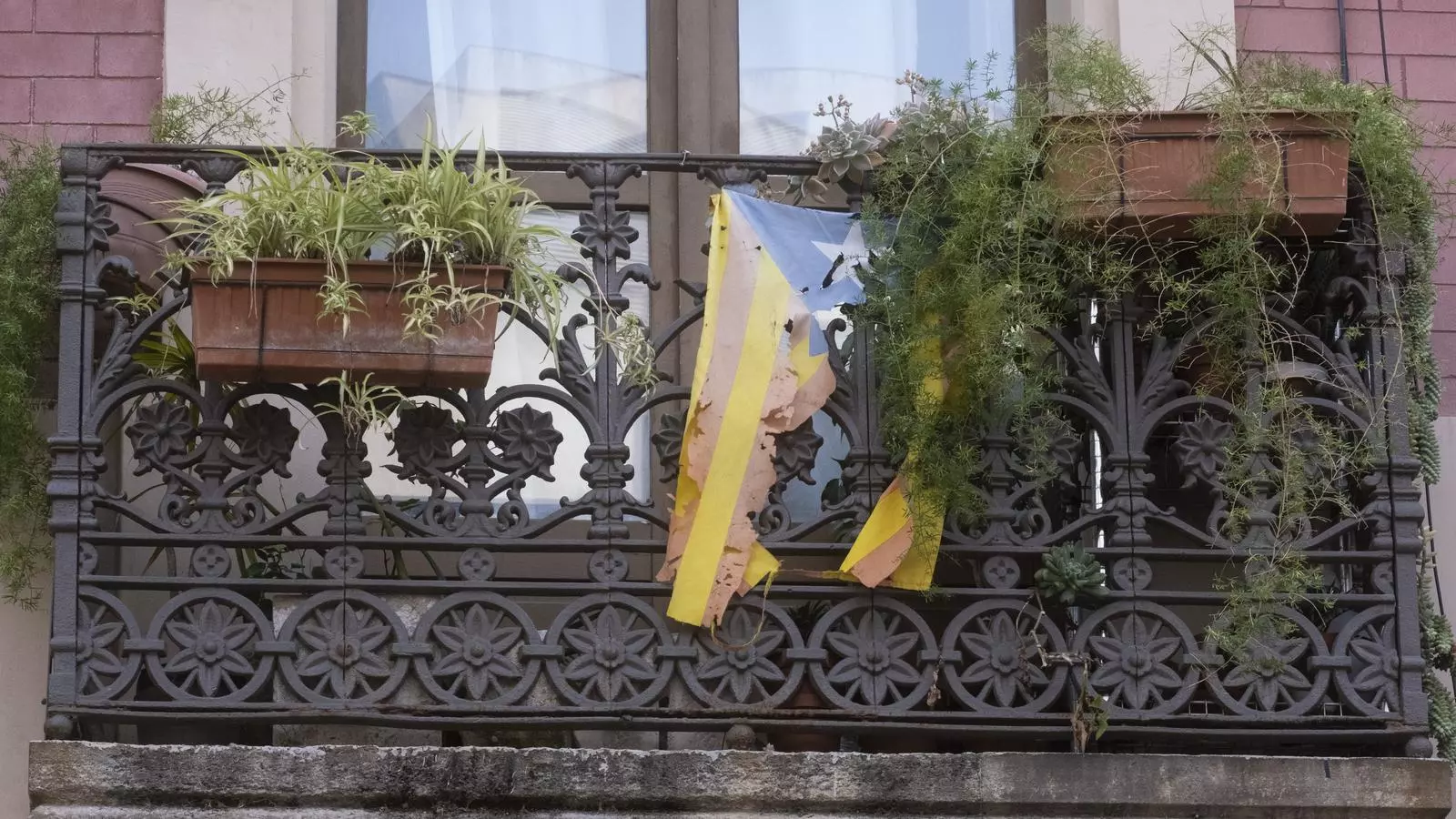 Una estelada rota cuelga de un balcó, en Barcelona.