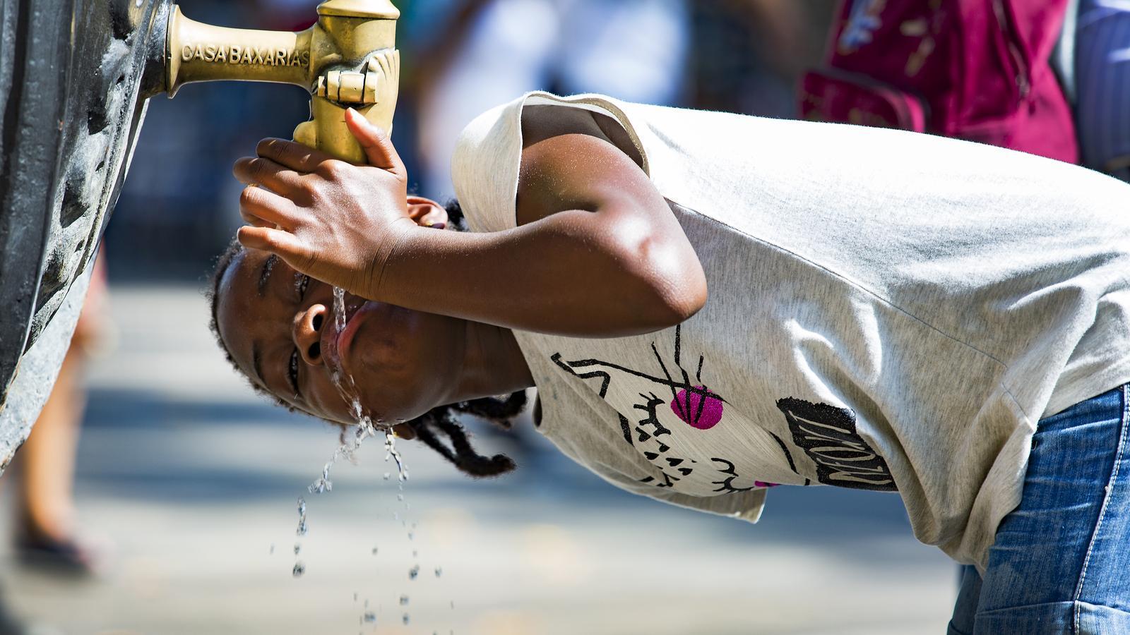 A girl drinking water from a fountain in Barcelona