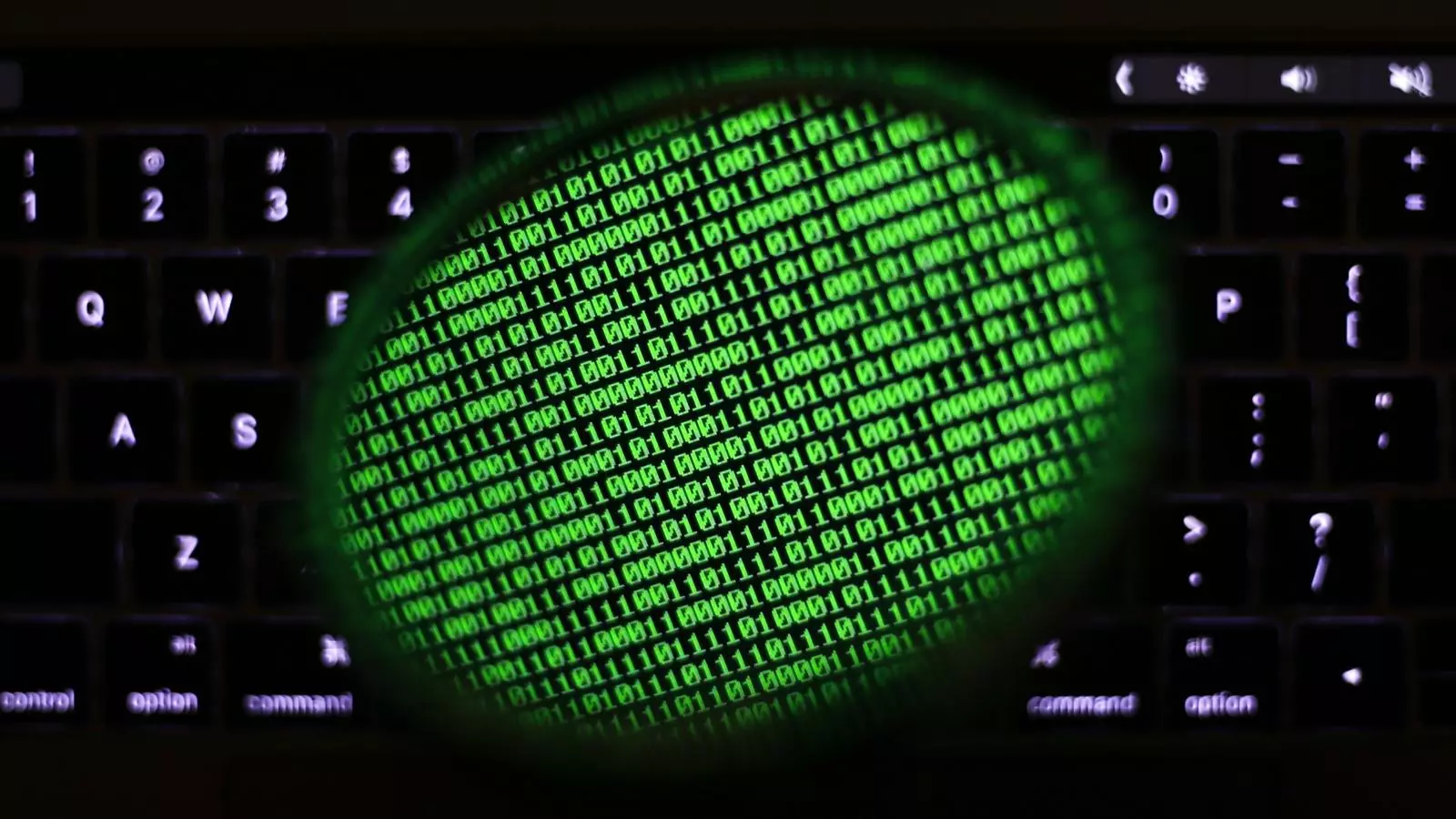 Un mirall reflexa una pantalla d'ordinador que mosta un codi binari.