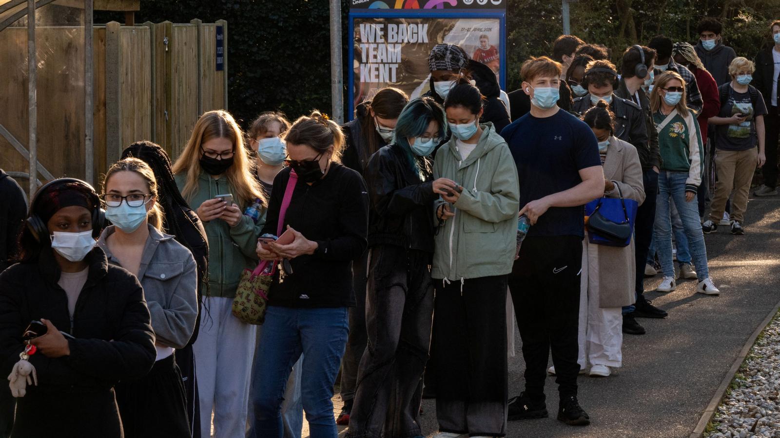 A group of people queue to get vaccinated at the sports center on the University of Kent campus.