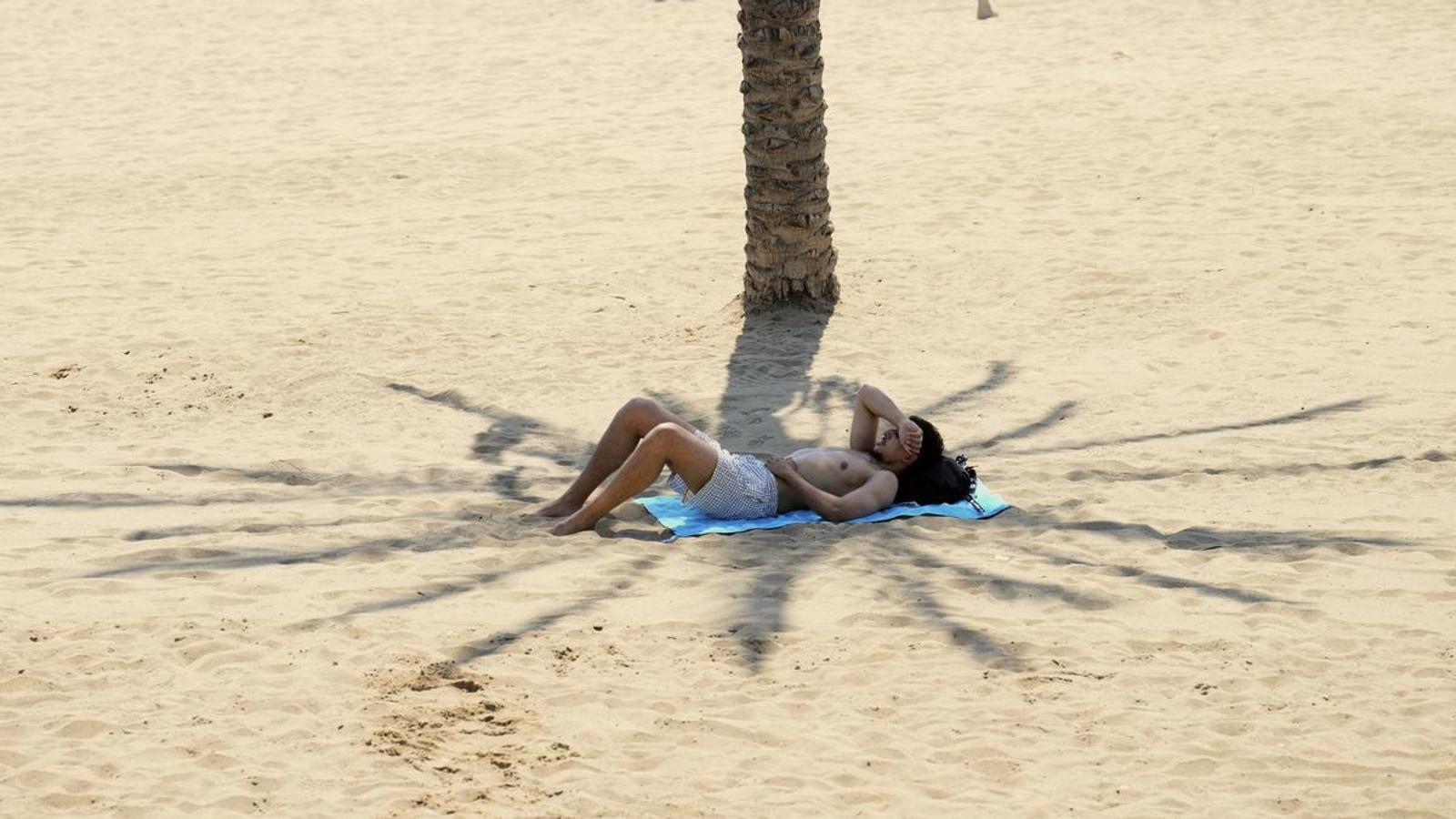 Un bañista se protege del calor, una playa de Barcelona, este jueves en que Cataluña sigue instalada en el calor extremo